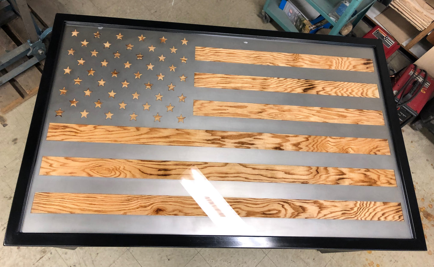 Metal framed american flag table with wood grain popping through the flag stripes and stars. Top down view